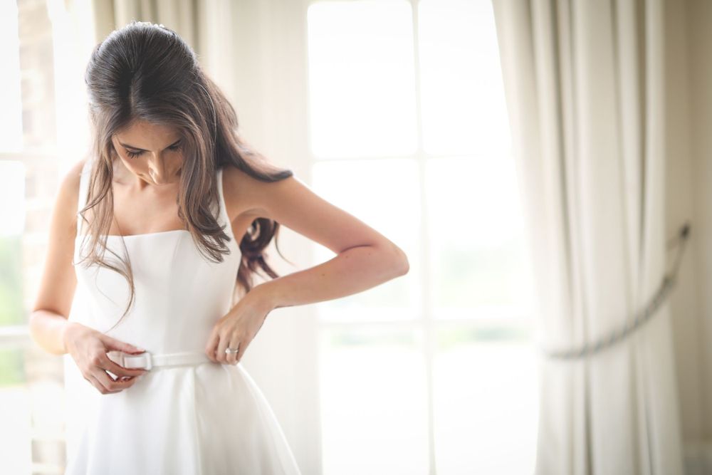 Detail shot of wedding dress fitting in a bright, window-lit room. Hedsor House Wedding Asian Wedding Photography