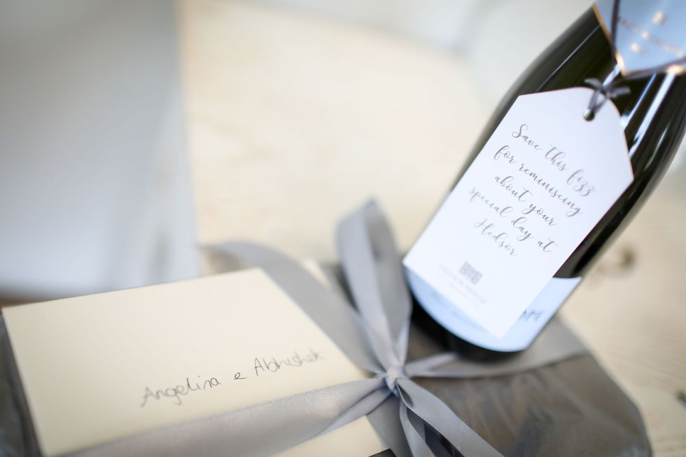 Close-up of handwritten wedding stationery and wine bottle with custom label. Hedsor House Wedding Asian Wedding Photography