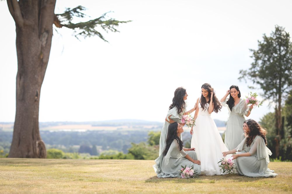 Wedding party relaxing on a grassy hillside with scenic countryside views. Hedsor House Wedding