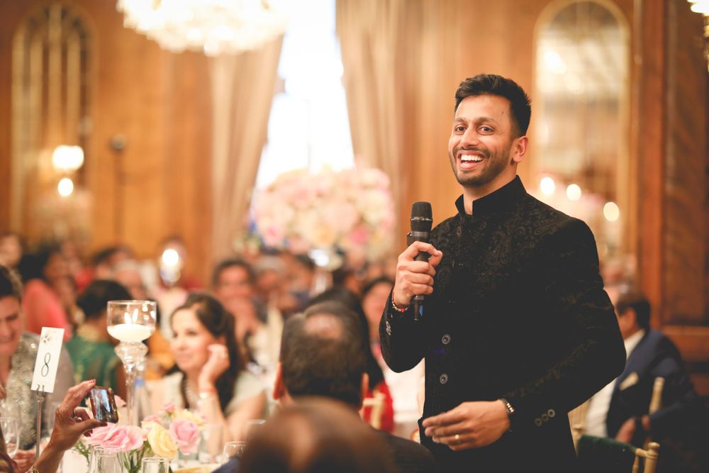 A joyful speech being given during an elegant wedding reception in a grand banquet hall. Hedsor House Wedding, Indian Wedding Photography