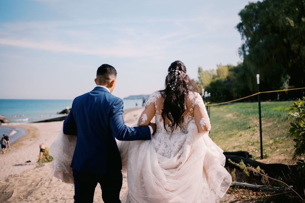 A couple in wedding attire walk hand in hand along a scenic coastal cliff path on their special day.