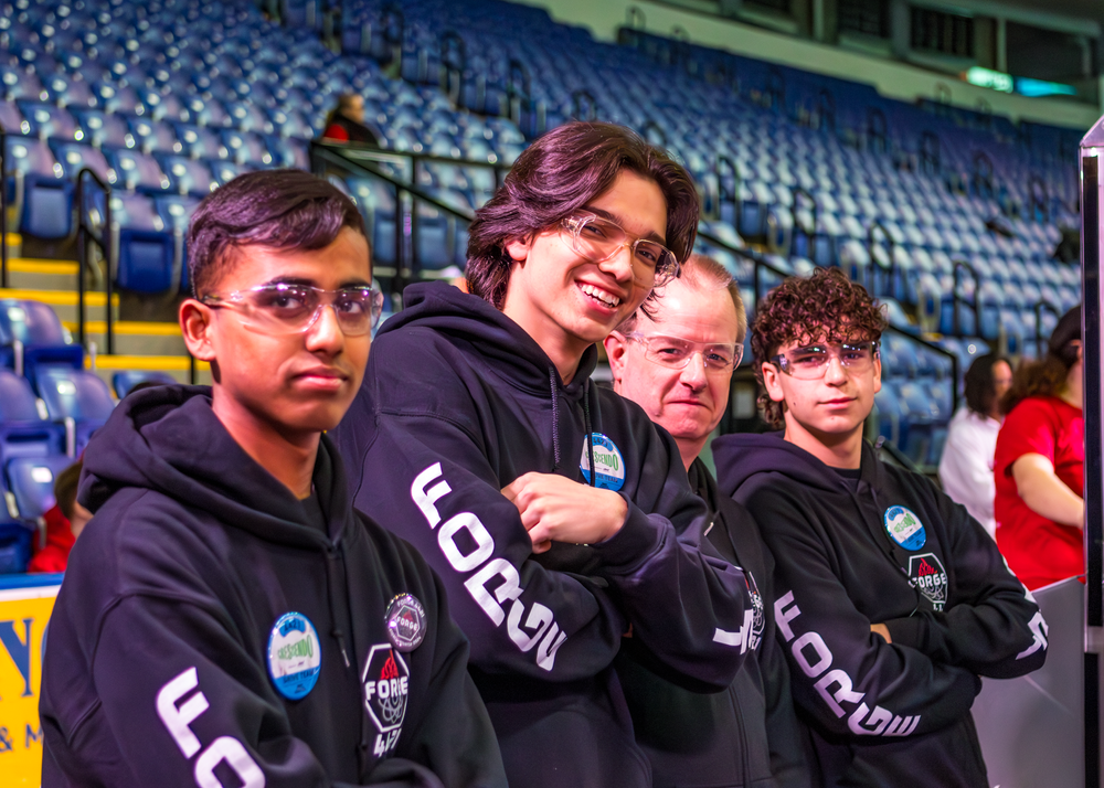 A group of esports players wearing black hoodies with "uDeck" branding pose together in an empty stadium.