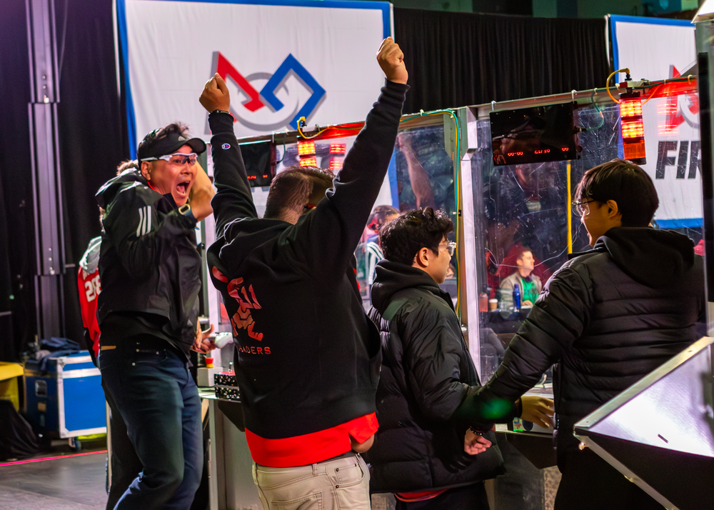 Esports competitors and fans gather around gaming stations at a competitive tournament event.