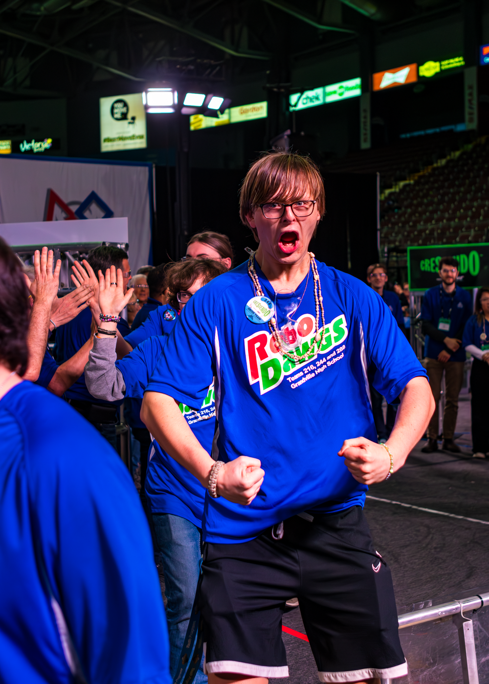 An excited player in a bright blue Pungo Donuts shirt celebrates during an esports tournament event.