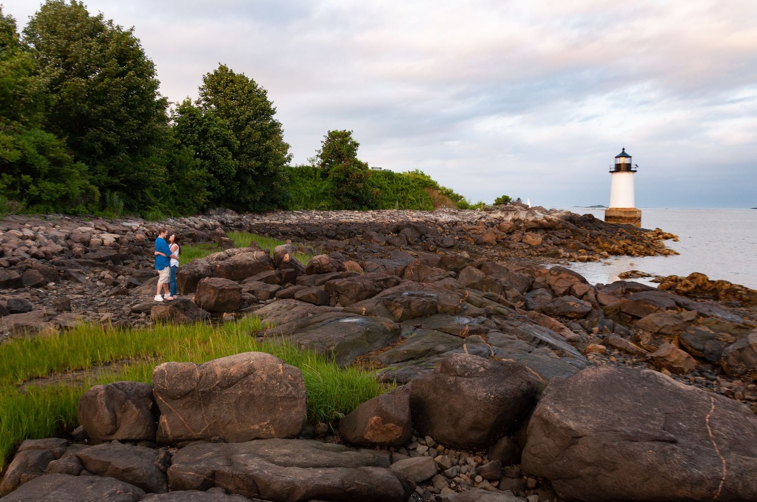 Leah Ramuglia photographs engagement portraits by Derby Wharf Lighthouse in Salem on Boston's North Shore with a dramatic rocky coastline.