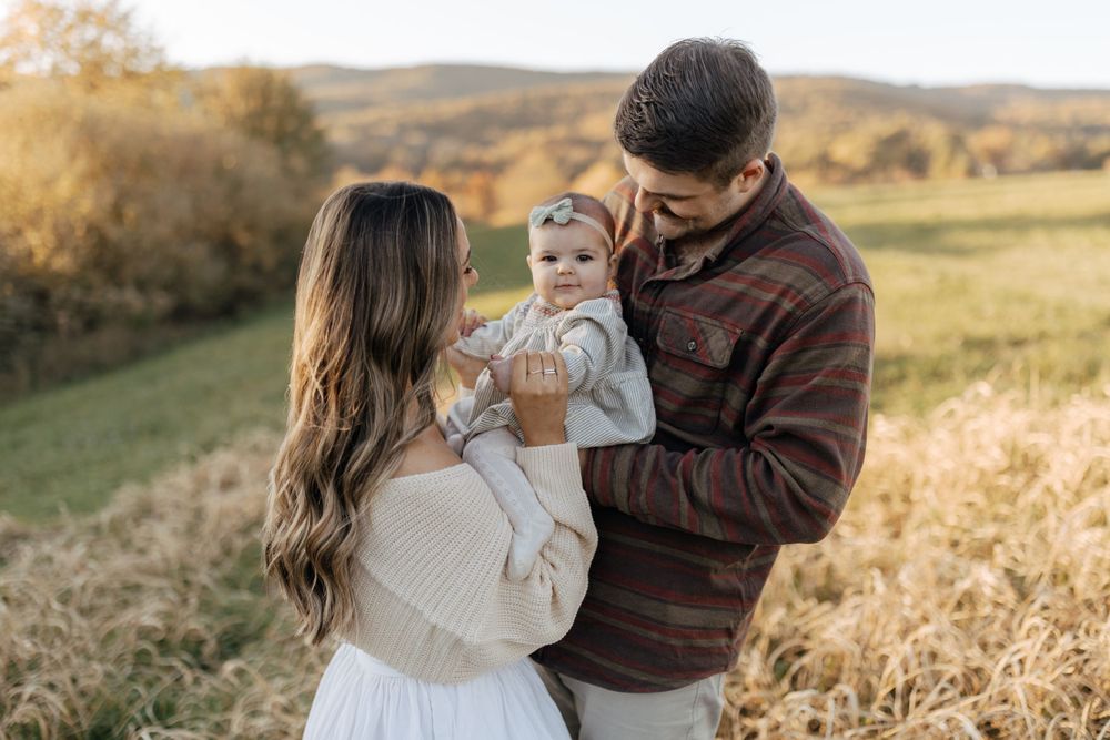 A tender family portrait taken in autumnal countryside with rolling hills in the background.