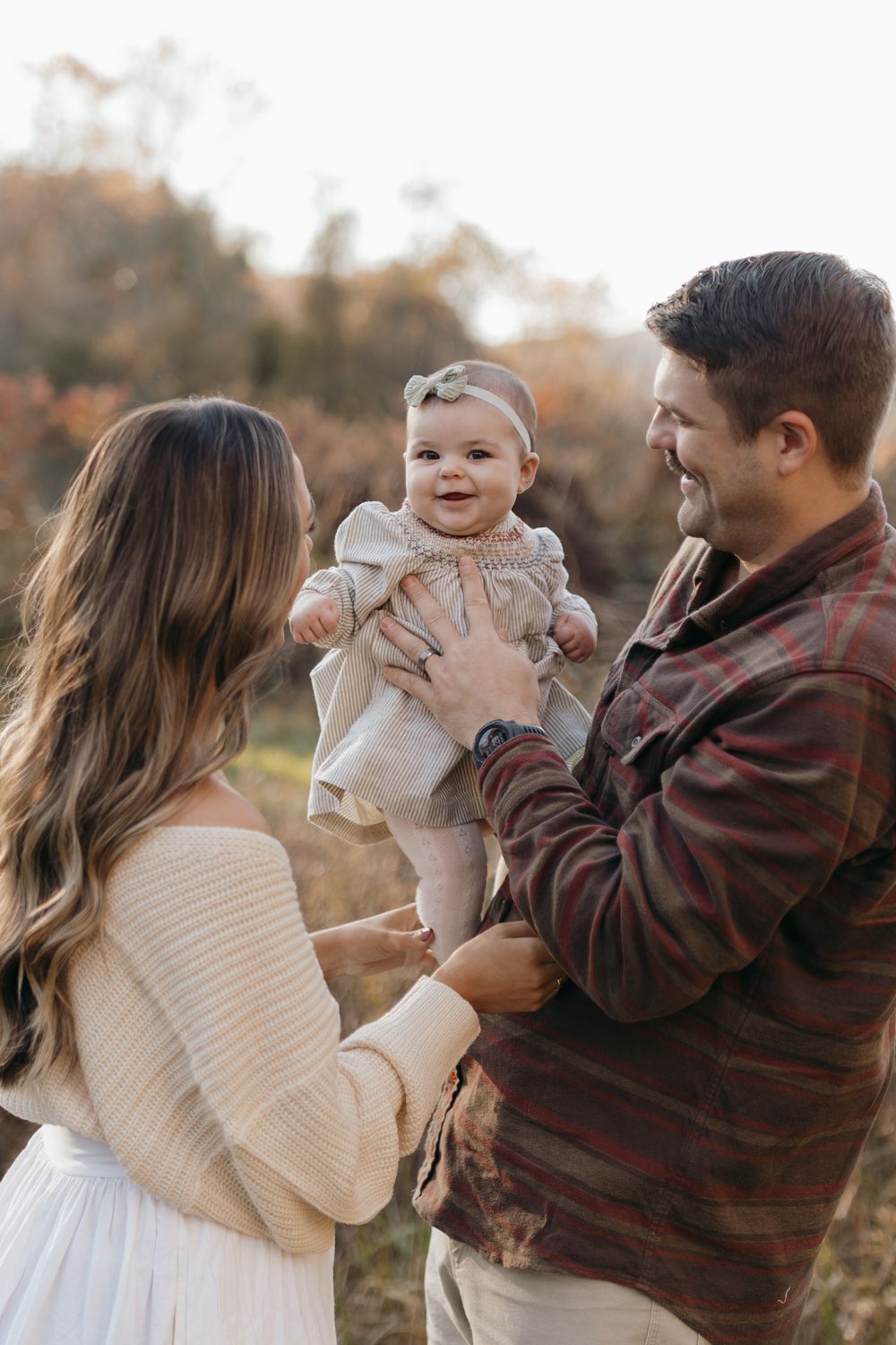 Sweet candid moment of a family sharing joyful laughter in a fall meadow setting.