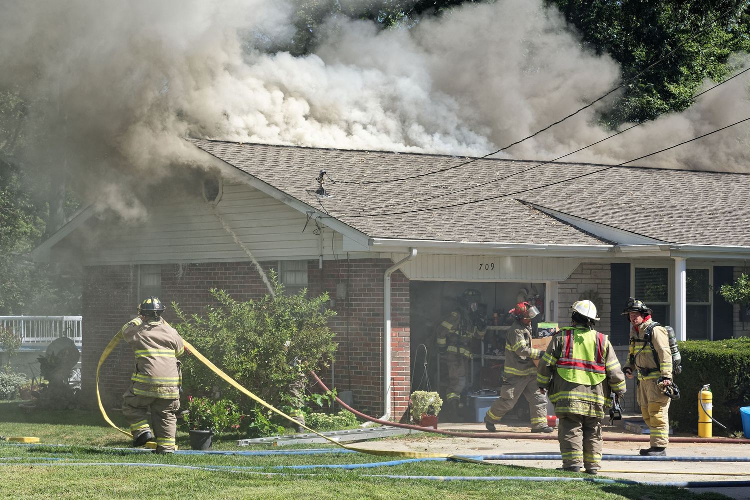 Firefighters battling heavy smoke and flames at a residential house fire.
