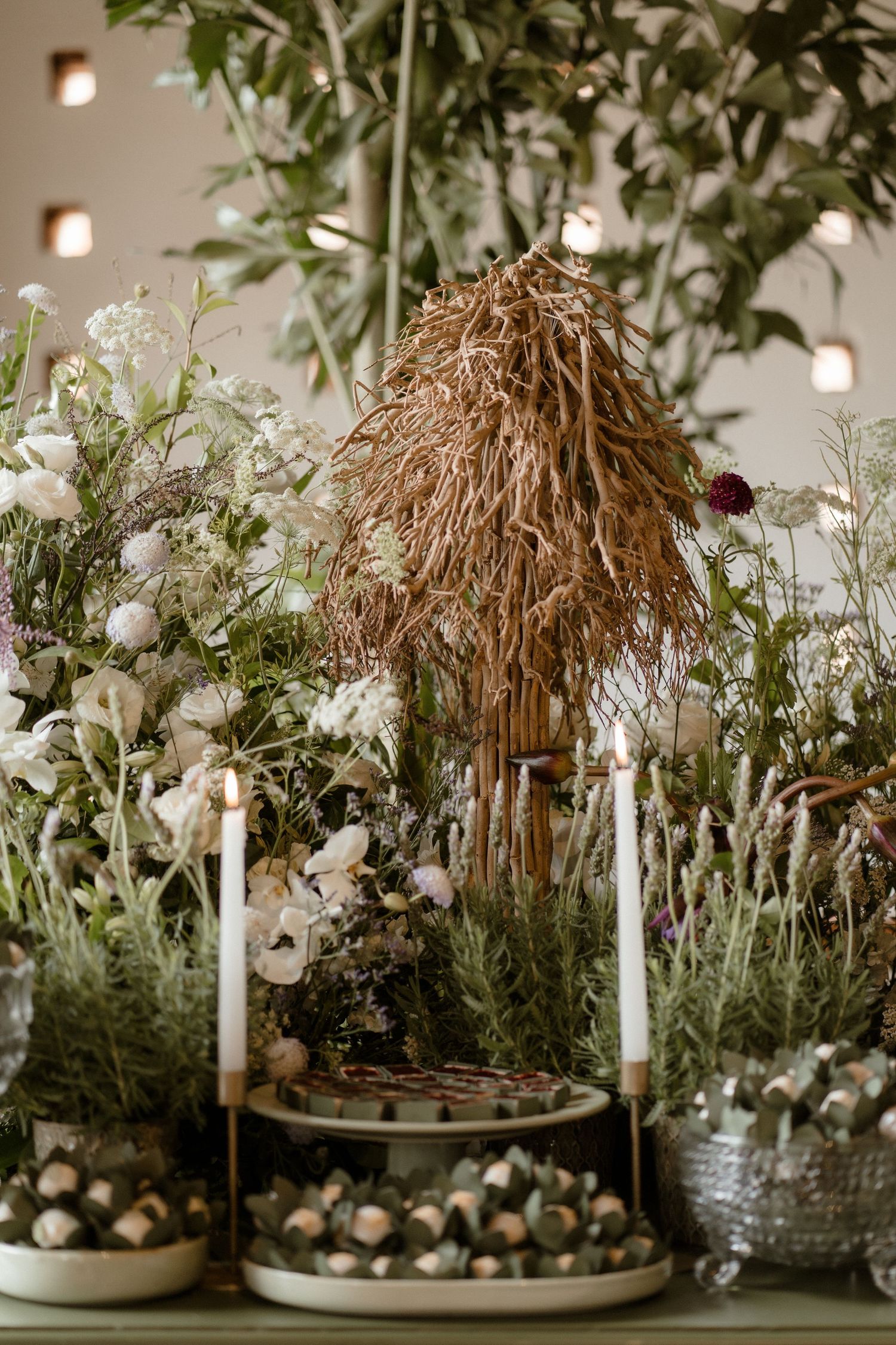 Rustic centerpiece display with white candles, florals and natural dried elements.