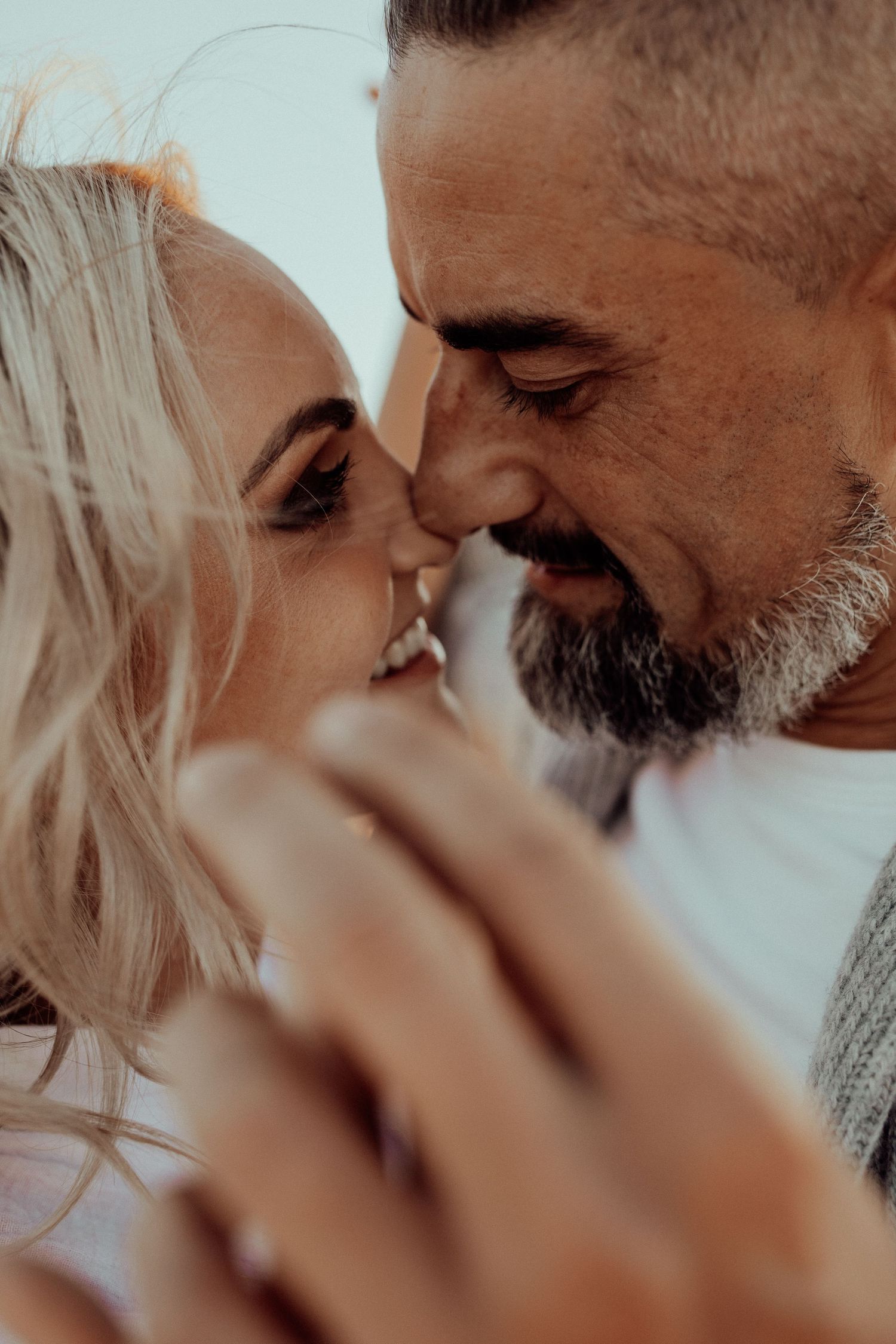 An intimate close-up of a couple smiling and touching foreheads in a tender romantic moment.