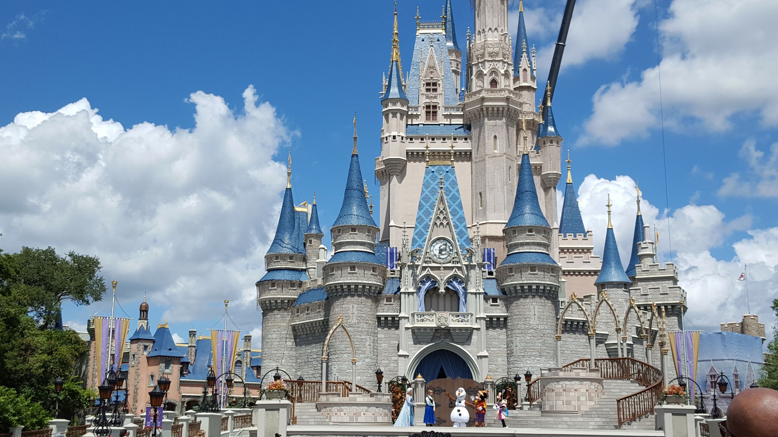 Cinderella Castle stands majestic against blue sky with white clouds at Walt Disney World's Magic Kingdom theme park.