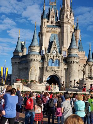 Cinderella Castle at Walt Disney World Magic Kingdom with blue spires and crowds gathered in front on a sunny day.