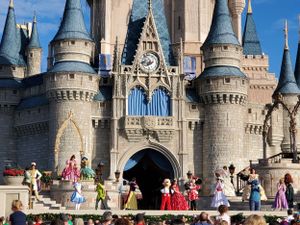 Iconic Cinderella Castle towers over crowds at Walt Disney World Magic Kingdom on a sunny day.