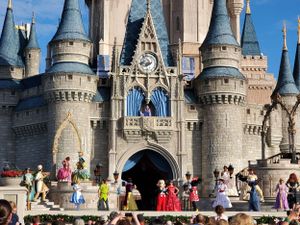 Visitors gather in front of Cinderella Castle at Walt Disney World's Magic Kingdom on a sunny day.