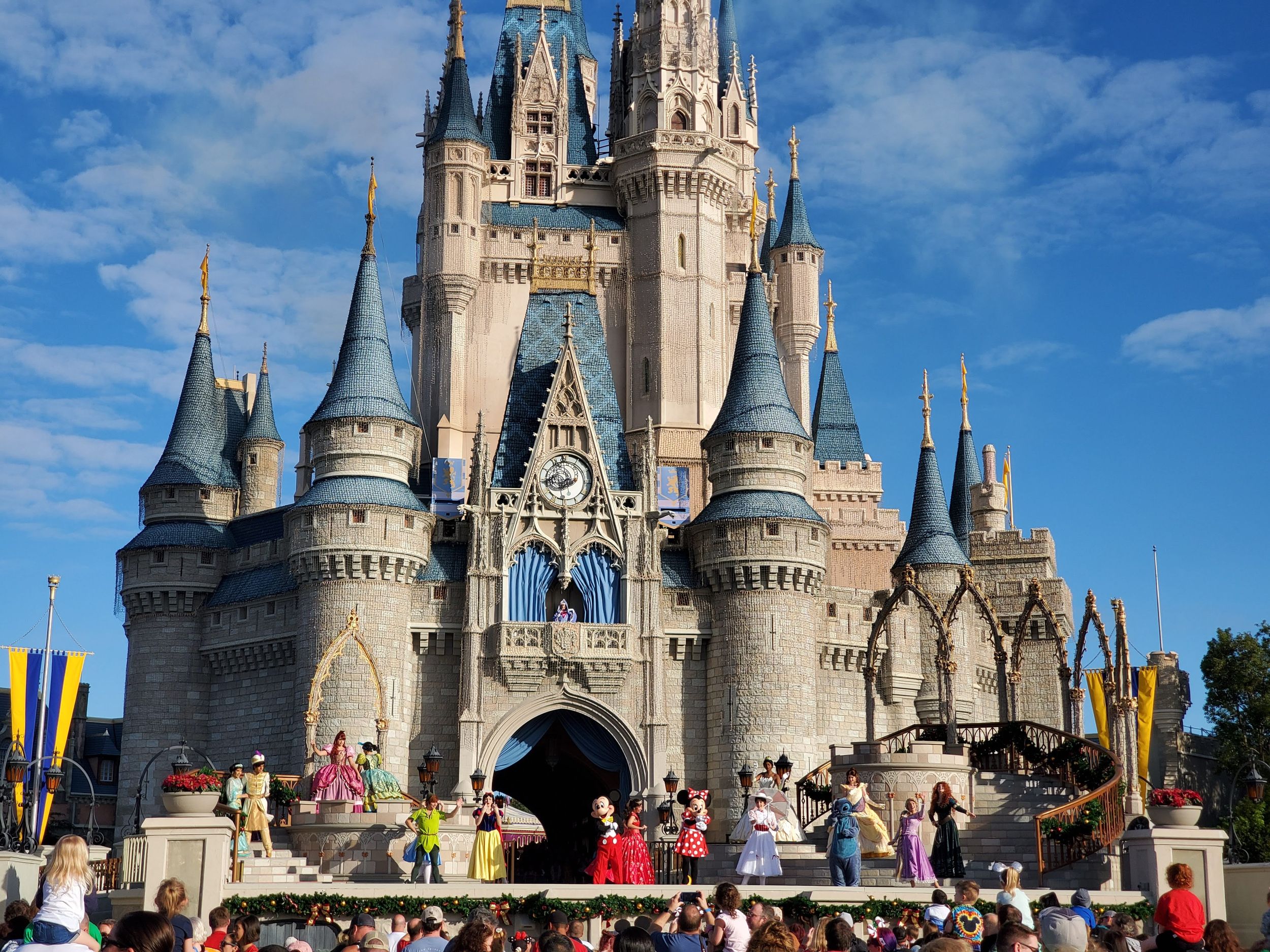 Cinderella Castle stands majestic against blue sky at Walt Disney World's Magic Kingdom theme park on a sunny day.