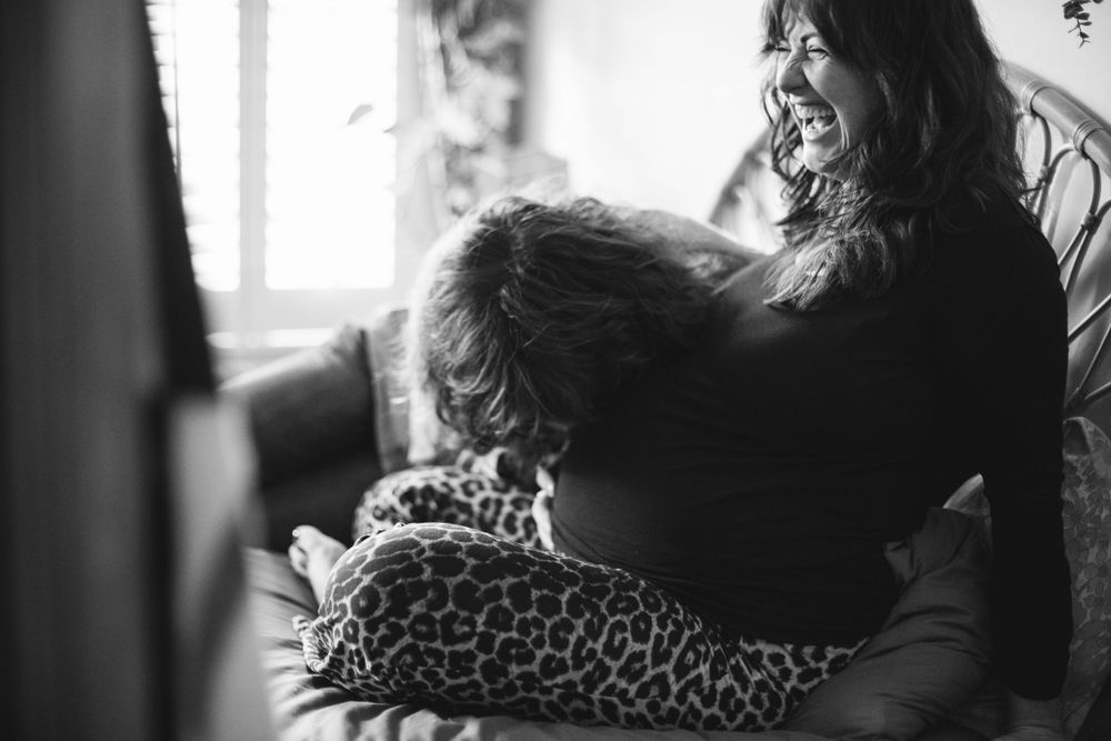 Black and white intimate moment showing tender embrace on couch with leopard print pillow.