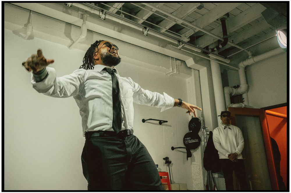 Performers in formal attire strike dynamic poses during rehearsal in industrial space. Portland music photographer