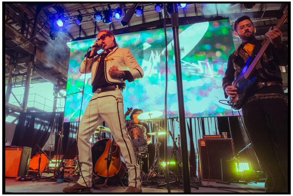 Band performing on stage with vibrant blue lighting and projected background visuals. Portland music photographer