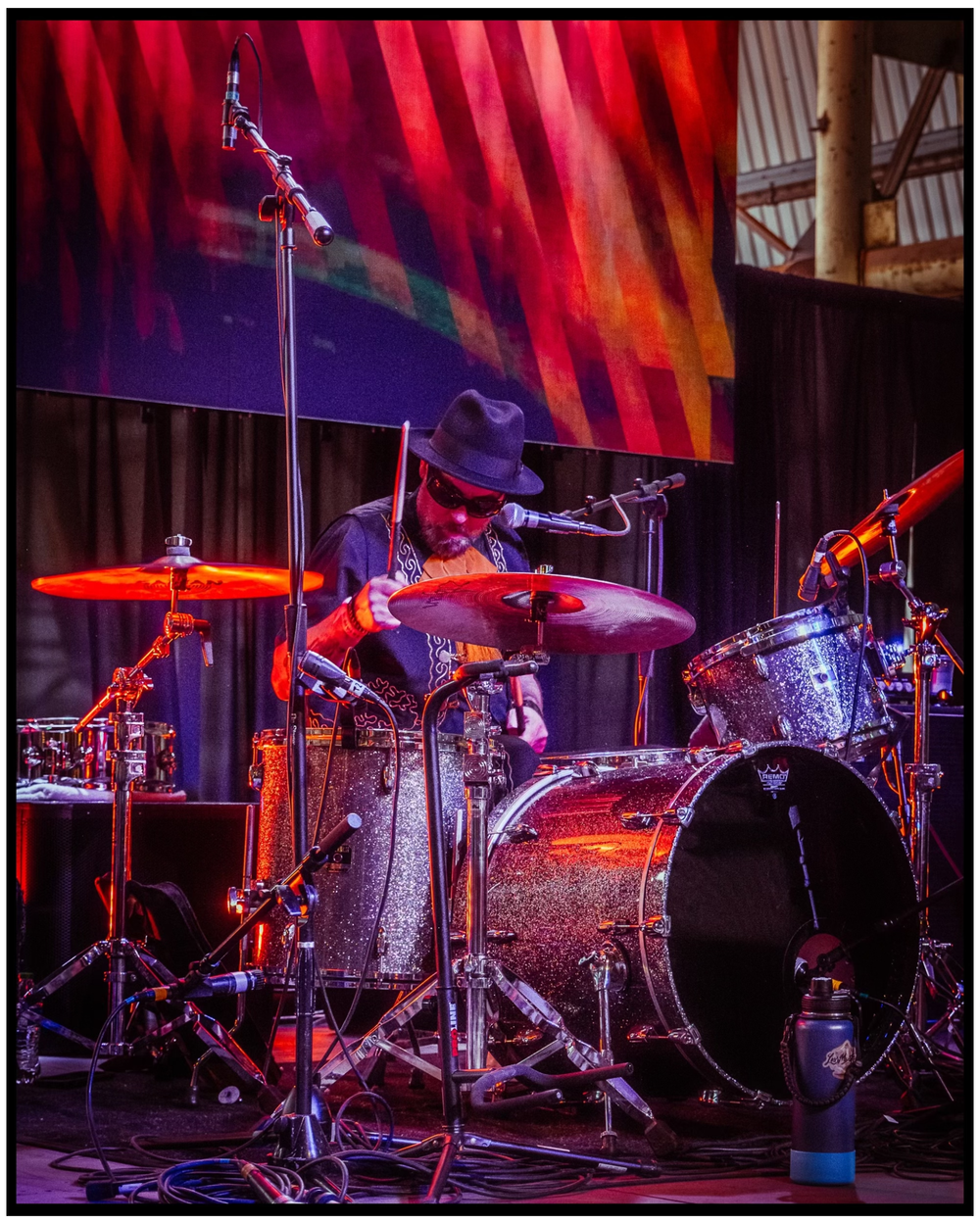 Illuminated drum kit on stage with dramatic red and purple lighting effects. Portland music photographer