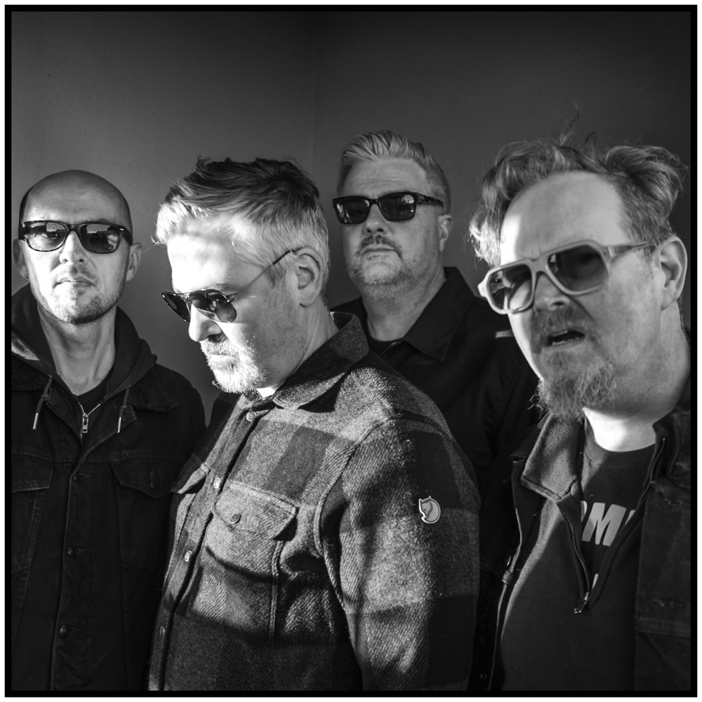 Black and white portrait of four band members wearing sunglasses and casual attire. Portland music photographer