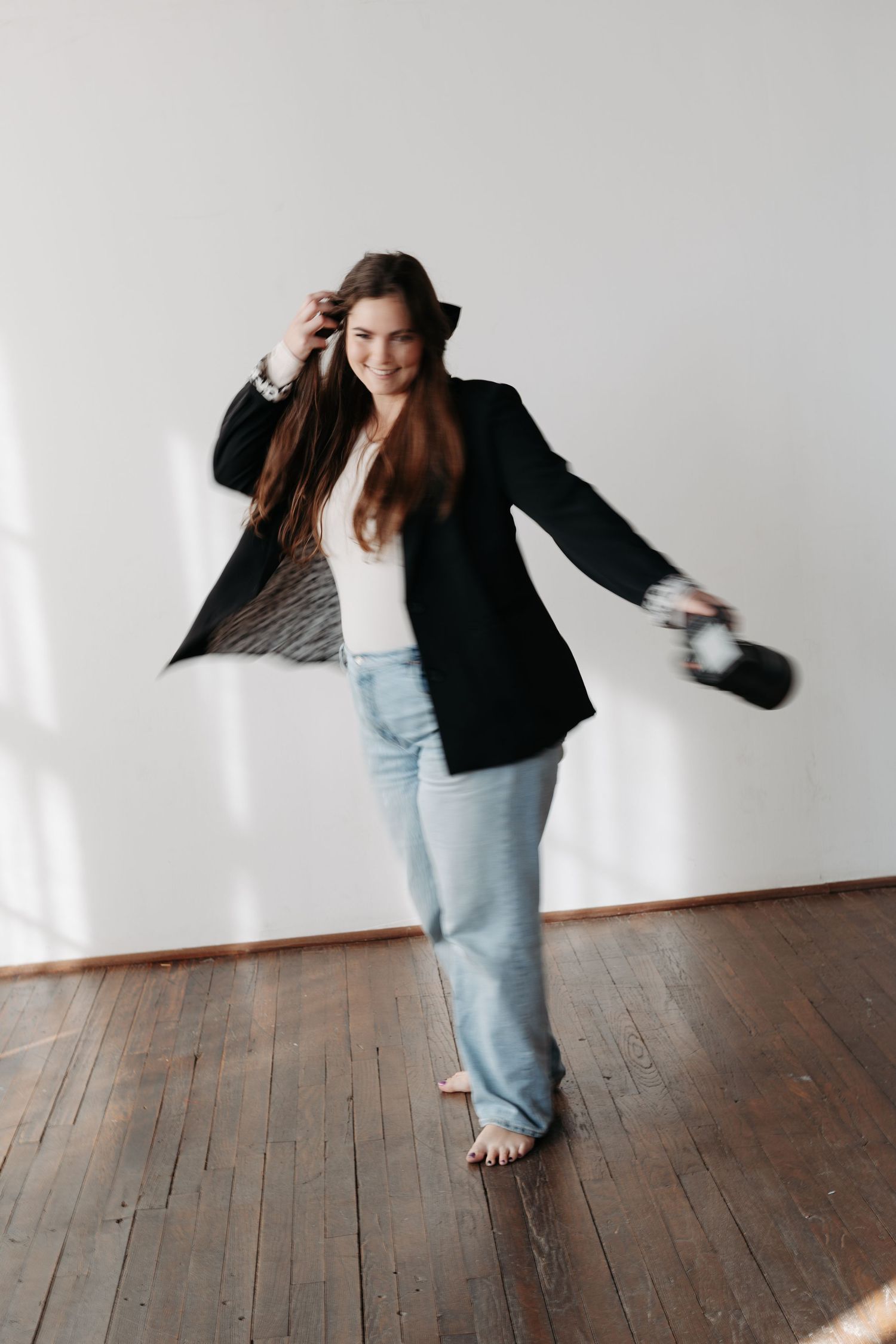 Photographer in casual attire sitting cross-legged with camera against pink wall.