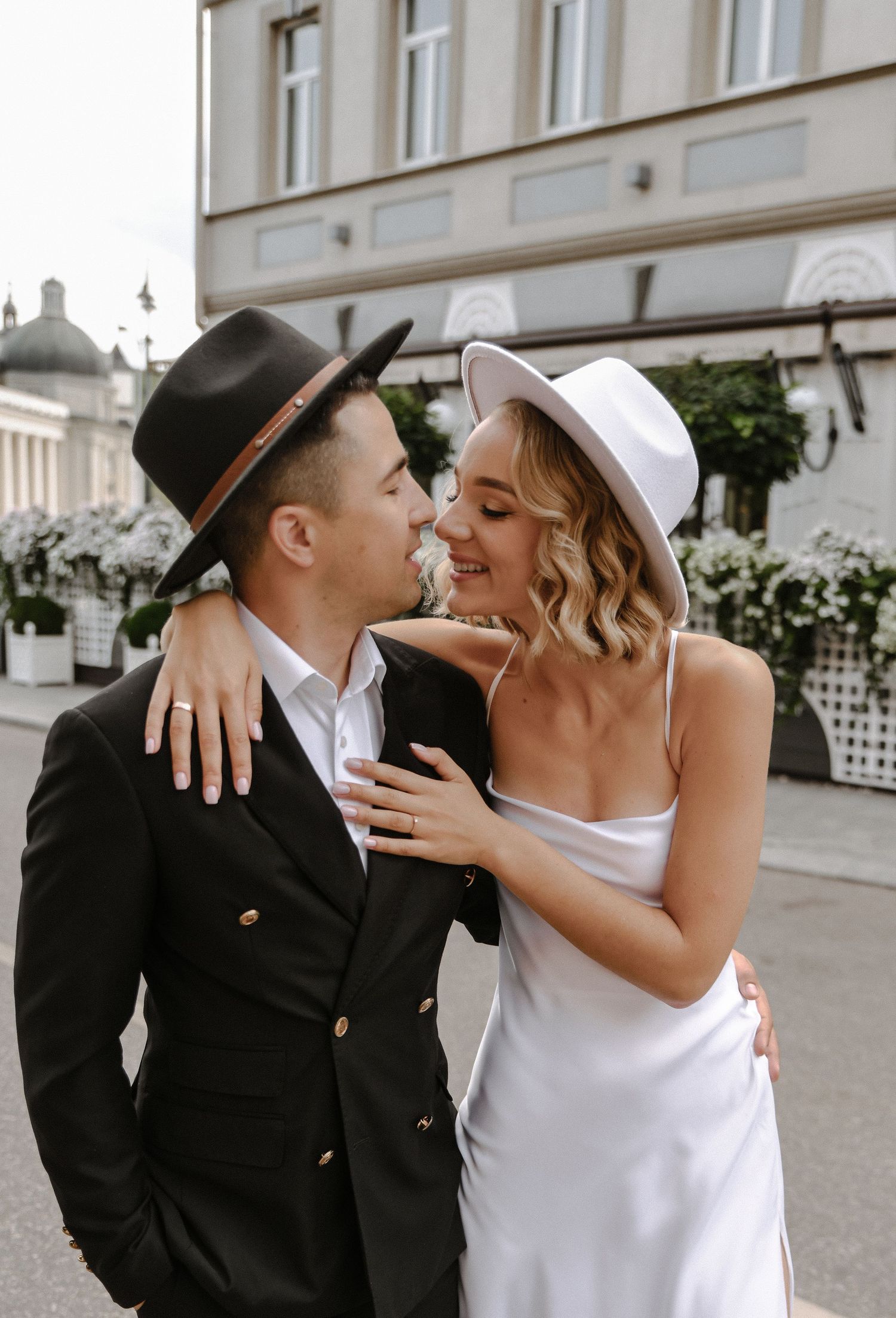 A stylish couple walks together in formal attire with vintage-inspired accessories.