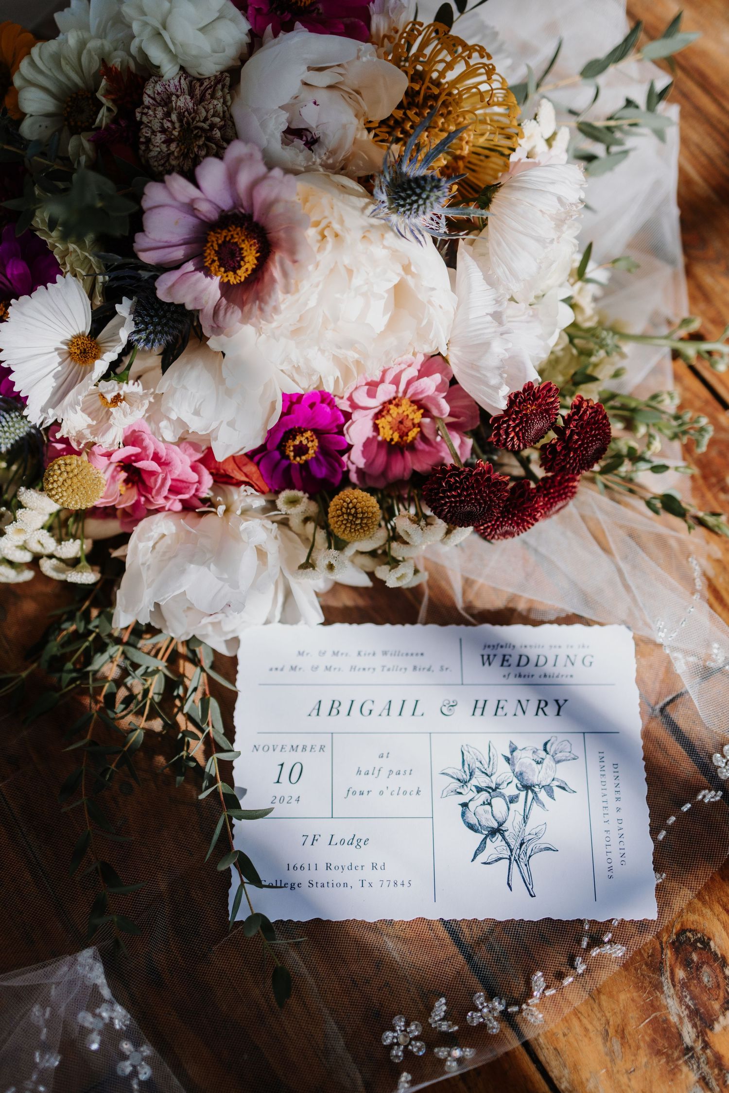 Elegant floral wedding invitation with white and burgundy flowers displayed with name cards.