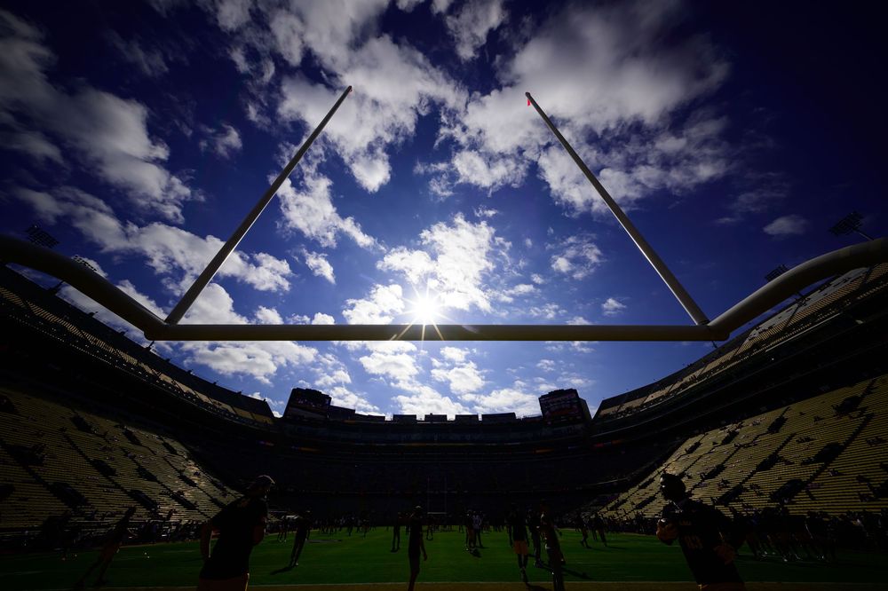 A dramatic time-lapse sequence of clouds moving over a sports stadium with bright sunlight and deep blue sky.