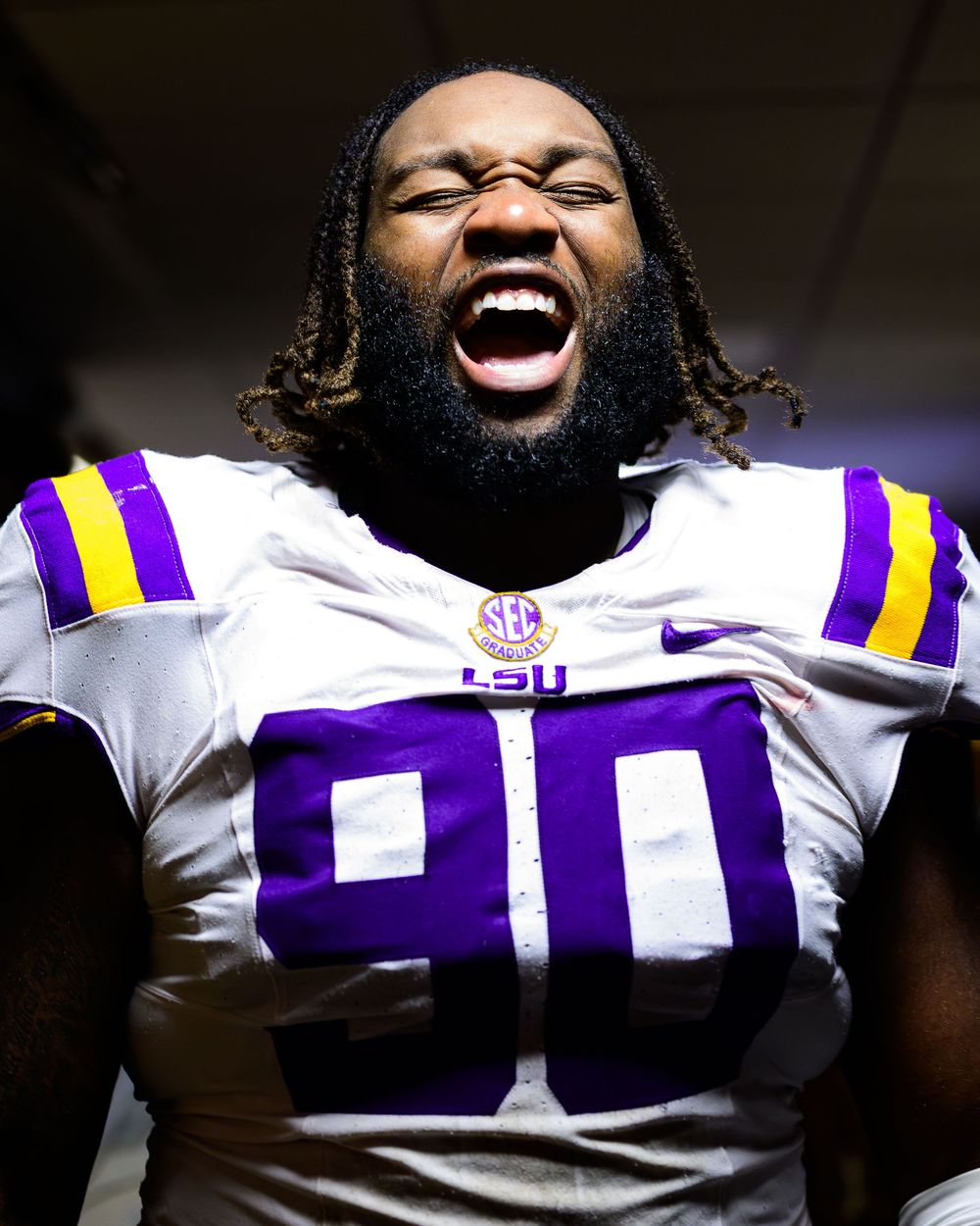 LSU football player celebrates enthusiastically in purple and gold uniform during game action.