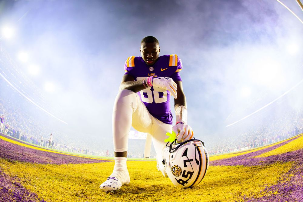 Low angle fisheye view of LSU football player with stadium lights creating dramatic atmosphere.