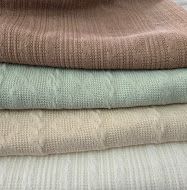 A collection of neatly folded linen fabrics in neutral earth tones arranged in a row showing different textures and weaves.