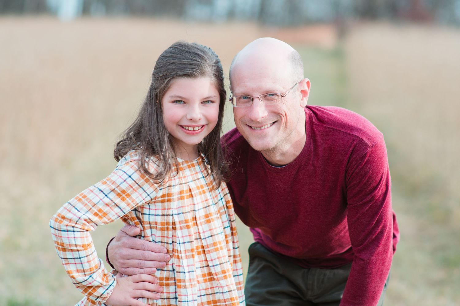 Father and daughter smiling together outdoors in casual clothing.