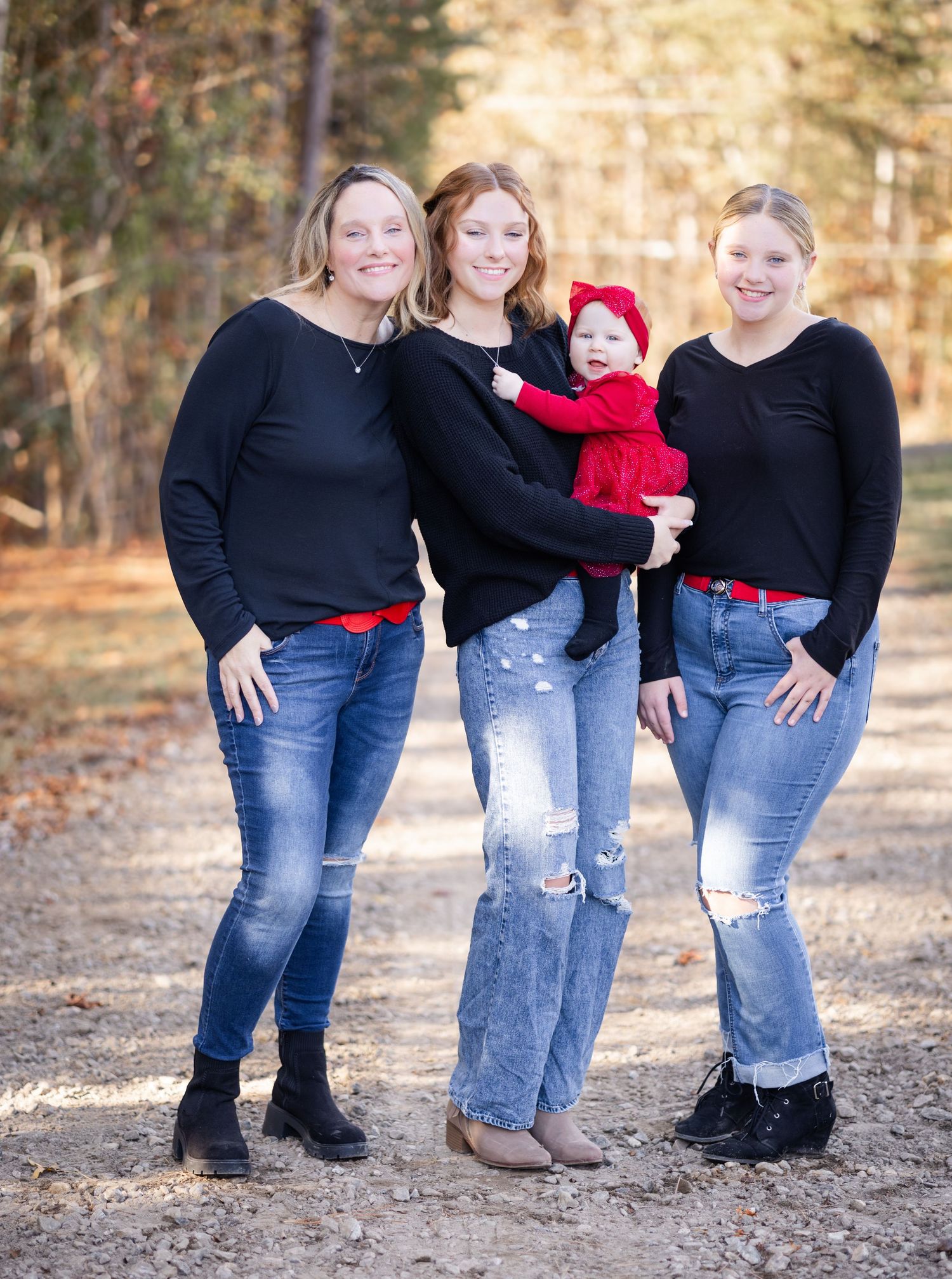 Group of four people in coordinating outfits standing together on forest path.