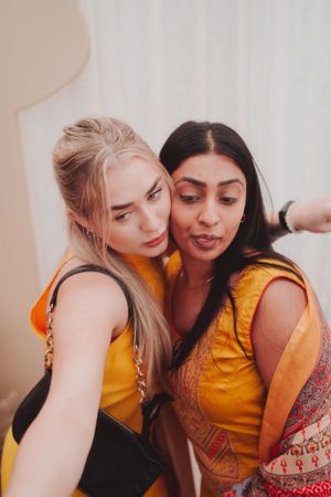 Friends wearing matching yellow outfits taking a casual selfie together.