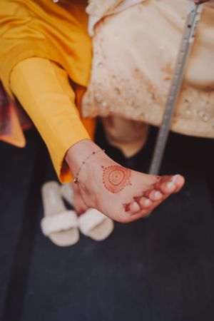 Close-up of intricate henna design on foot with yellow clothing detail.