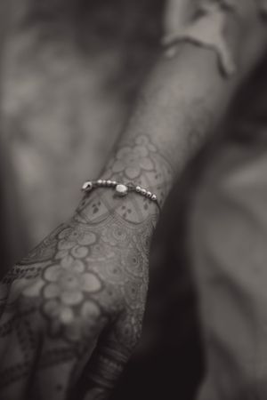 Black and white photo of intricate henna patterns with delicate bracelet detail.