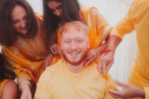 Three friends in yellow outfits share a joyful moment during a celebration.