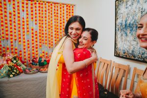 Two people embracing warmly at a celebration with orange decorations in the background.