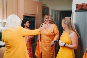 Group celebrating in a kitchen while wearing matching yellow and orange outfits.
