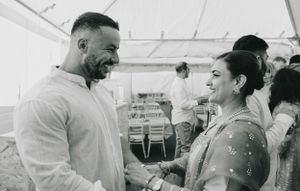 Black and white photo of a couple sharing a joyful moment at an outdoor celebration.