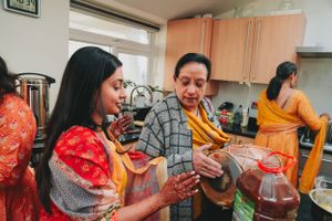 Group celebrating with traditional instruments and colorful attire in a kitchen.