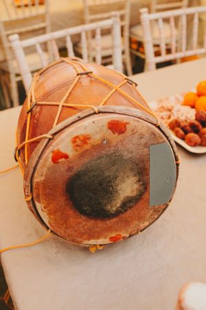 Traditional Indian drum with leather surface and rope bindings on a white table.