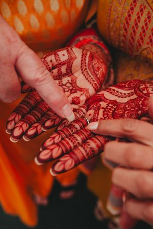 Detailed view of traditional mehndi artwork being drawn on hands with henna.