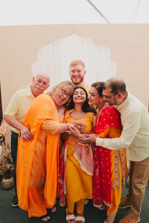 A family group shares a candid moment of laughter while wearing coordinated Indian festive attire.
