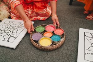 Colorful powders arranged in a round wooden bowl next to a mandala coloring page.