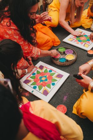Close-up of colored sand art creation with participants working on mandala designs.