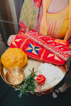 Traditional plate with offerings including yellow bread, red cloth, and decorative elements.