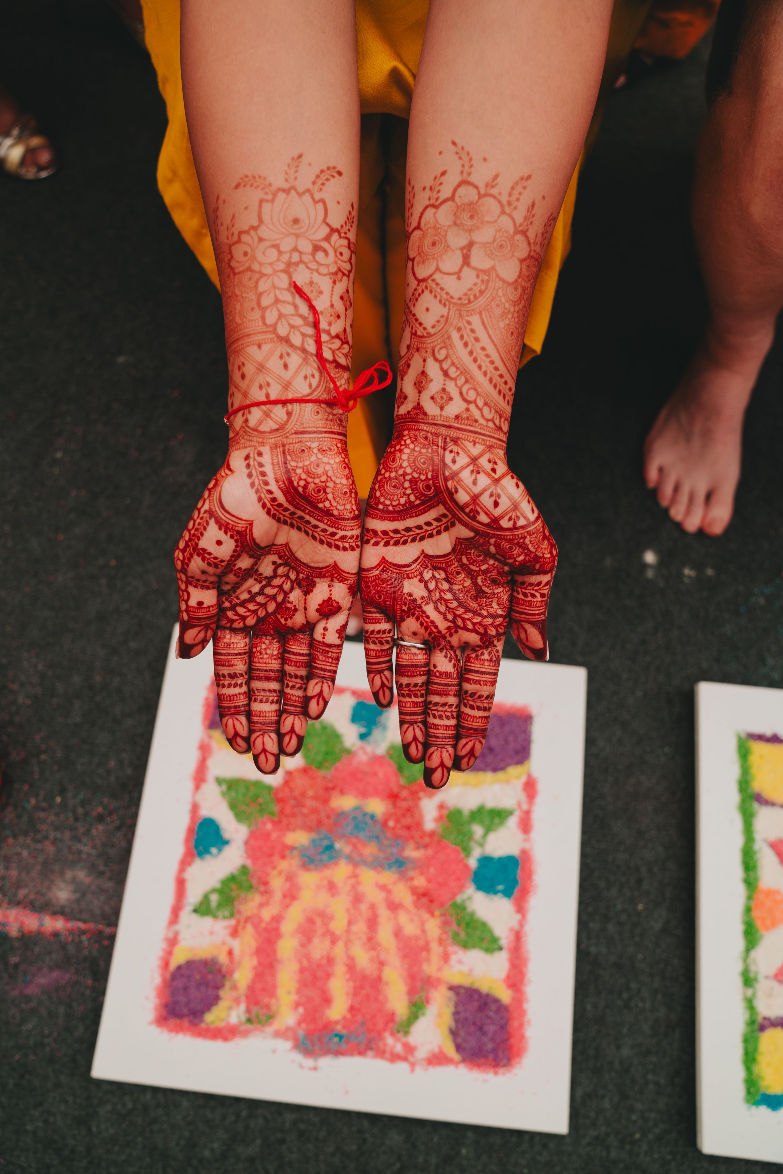 Detailed mehndi henna designs decorating both palms over colorful artwork.