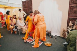 People in vibrant orange traditional attire embrace during what appears to be a cultural ceremony or celebration.