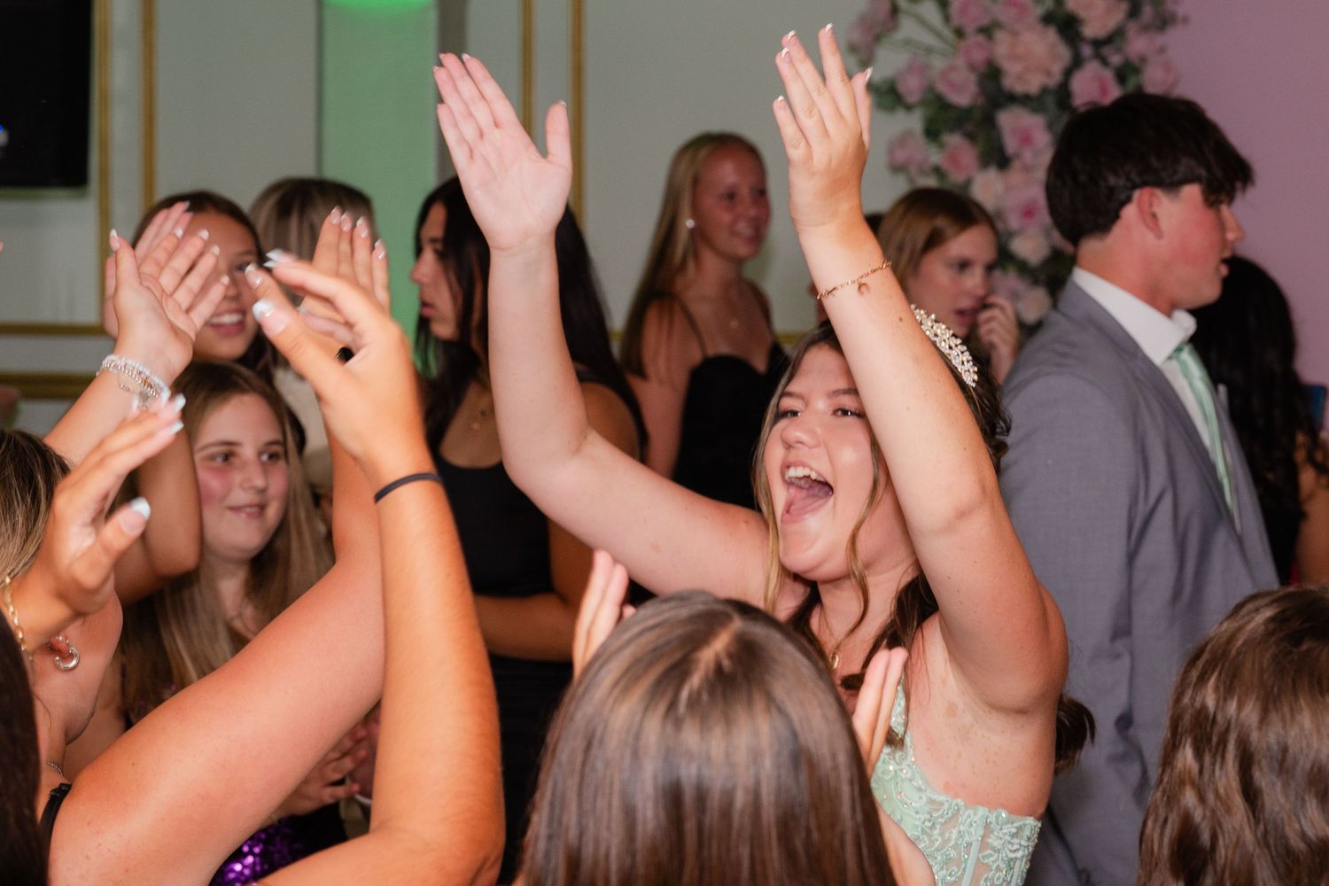 Crowd of party guests raising hands and cheering enthusiastically at celebratory event.